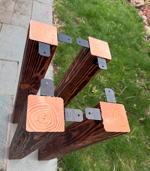 Four 4×4 legs laid flat showing Simpson L-brackets attached at tops