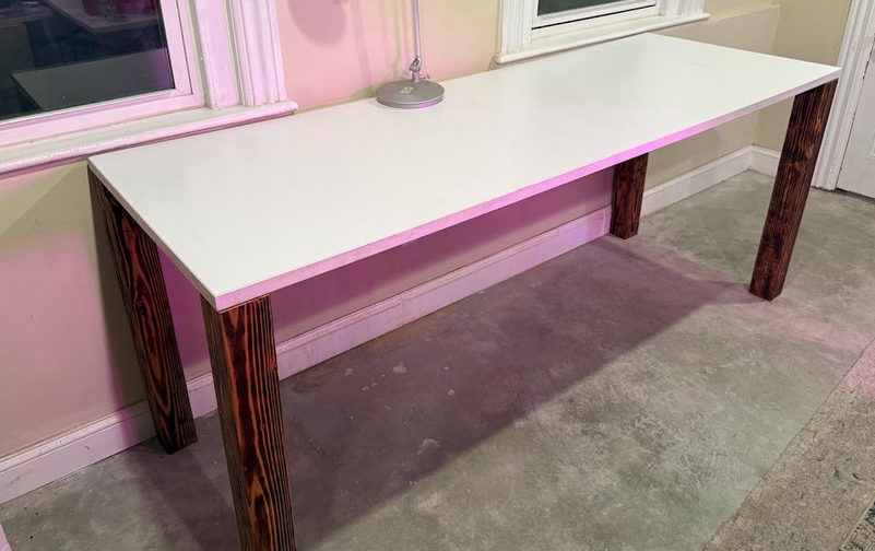 Completed custom desk — white Kimball Priority commercial top on four yakisugi 4×4 legs, finished room shot